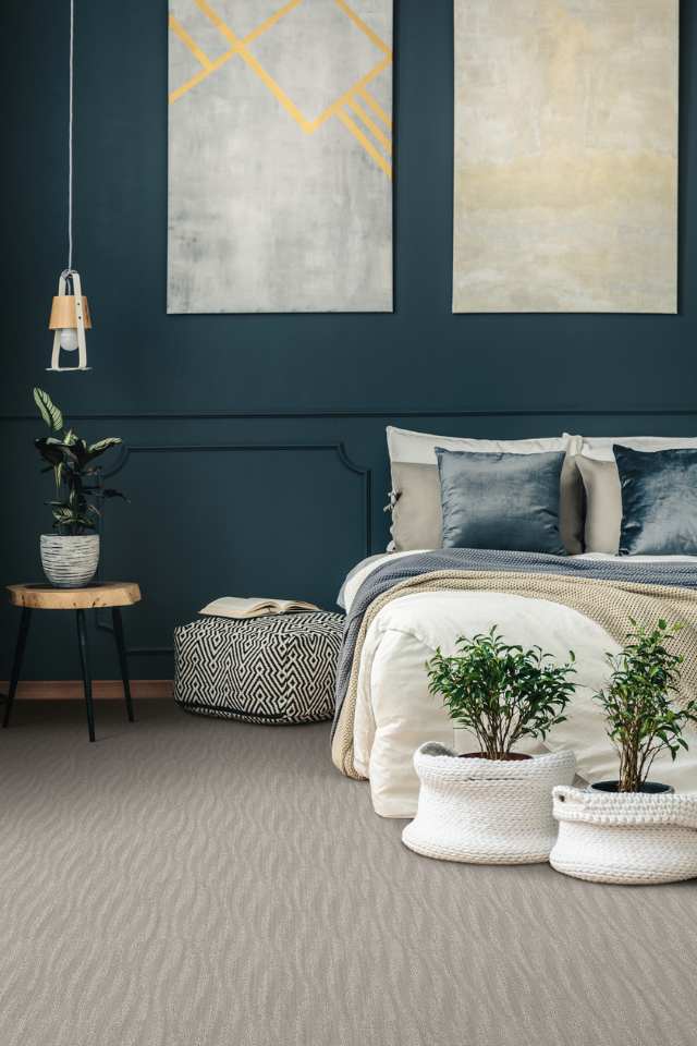 gray wavy patterned carpet in bedroom with navy blue accent wall and artwork